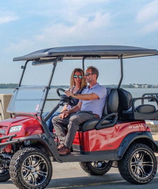 A couple driving an etto Leisure Cars cart along the Charleston waterfront
